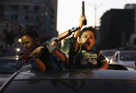 Palestinian children hold guns as they celebrate with others what they said was a victory over Israel, following a ceasefire in Gaza City, August 26, 2014.